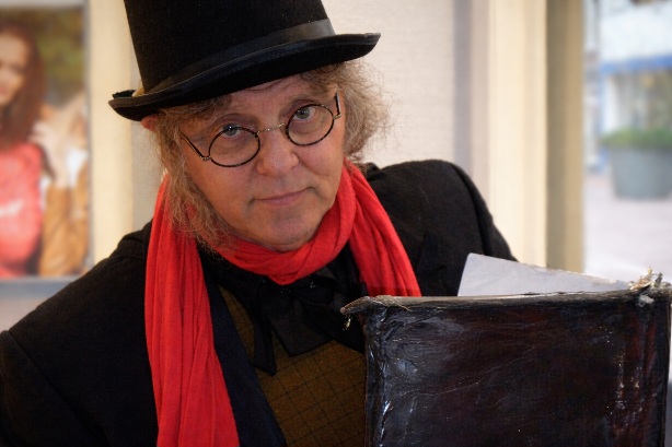 Dickens personage in victoriaans kostuum met hoge hoed op kerstmarkt